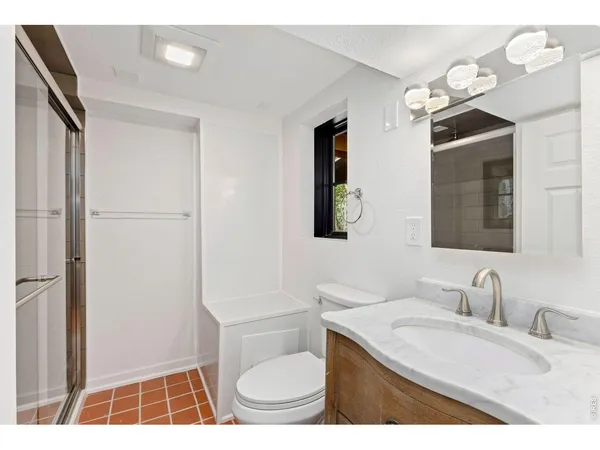 a bathroom with a granite countertop sink toilet a mirror and shower