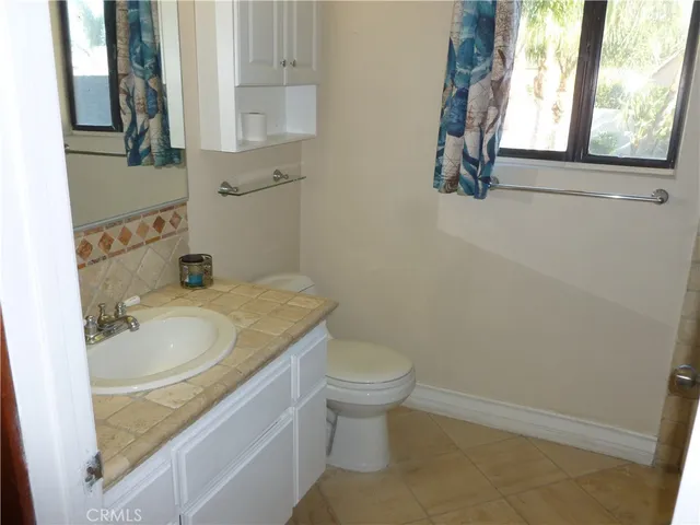 a bathroom with a granite countertop sink and a toilet
