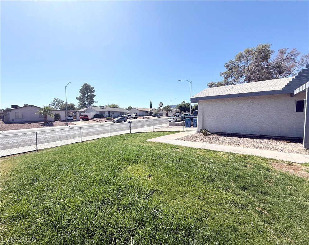 616 Greenway Road Henderson, NV 89002 - Photo 32 of 32 Green lawn leading to a paved street with a chain-link fence.