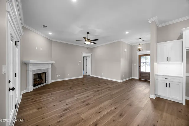 an empty room with wooden floor fireplace and windows
