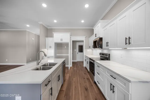 a kitchen with stainless steel appliances granite countertop a sink a stove top oven a counter space and cabinets