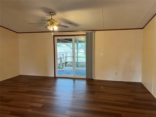 a view of an empty room with wooden floor and a chandelier