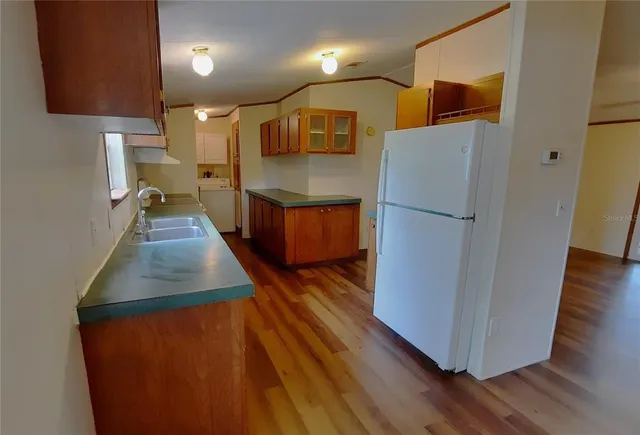 a kitchen with stainless steel appliances granite countertop a refrigerator a stove and a wooden floors