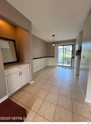 a view of a refrigerator in kitchen and an empty room with wooden floor