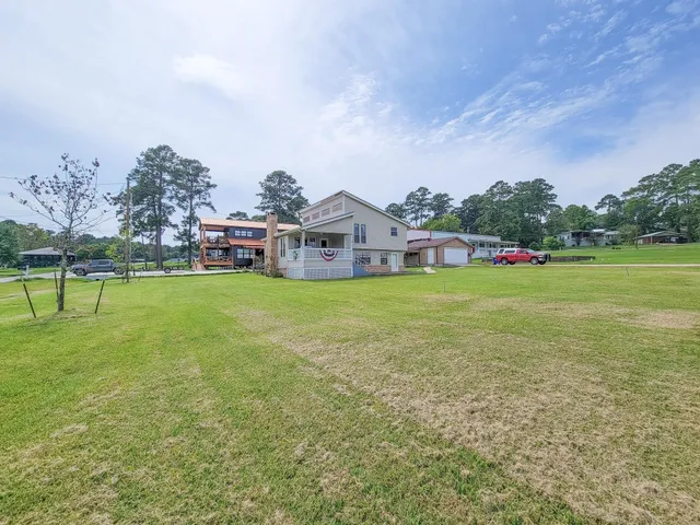 a view of a house with a big yard and large trees