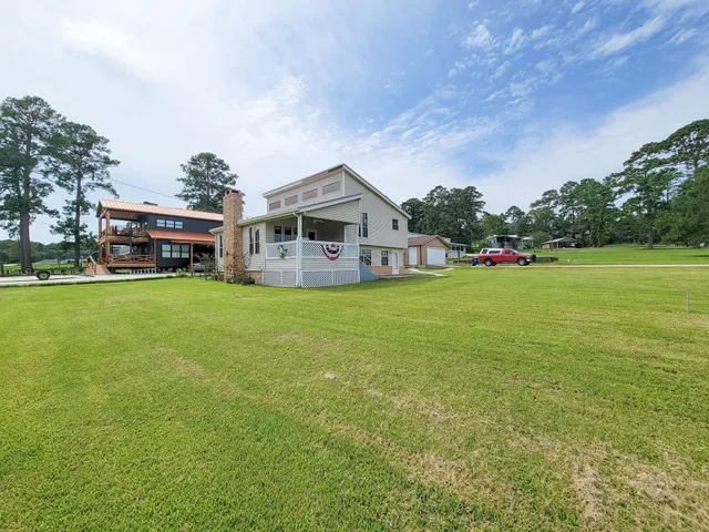 a view of a house with a big yard and large trees