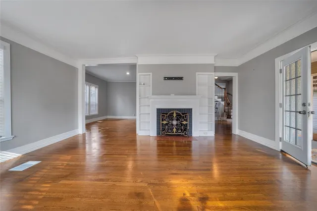 a view of an empty room and kitchen with a fireplace