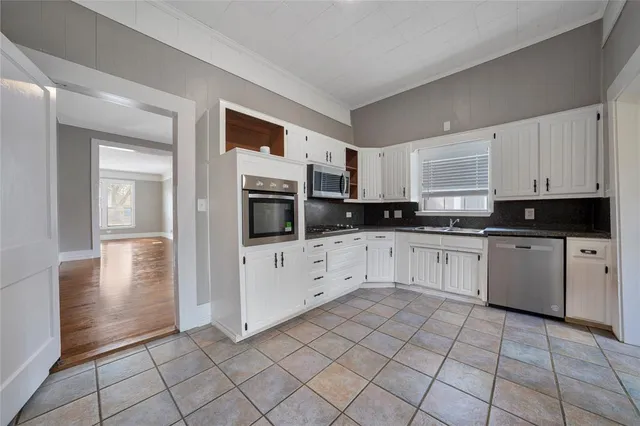 a kitchen with white cabinets a sink and white appliances