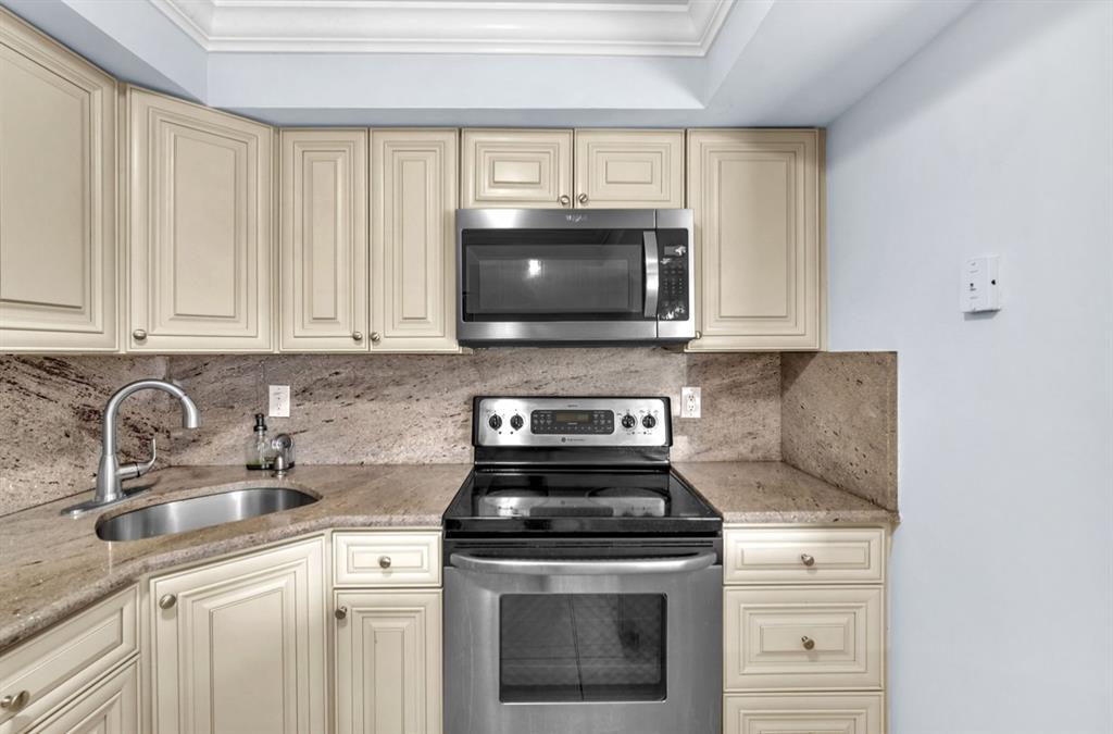1321 Partridge Close, Unit 60 Pompano Beach, FL 33064 - Photo 13 of 28 a kitchen with granite countertop a stove top oven microwave and cabinets