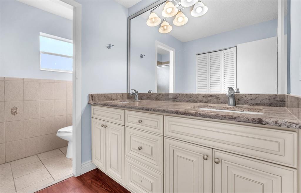 1321 Partridge Close, Unit 60 Pompano Beach, FL 33064 - Photo 24 of 28 a bathroom with a granite countertop sink a toilet and a mirror