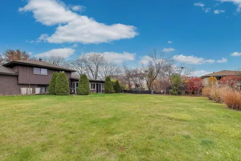 a view of a house with a big yard and large trees