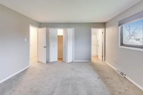 a view of an empty room with closet and a window