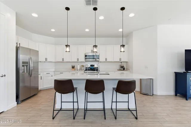 a kitchen with stainless steel appliances a table chairs refrigerator and microwave