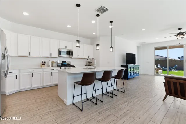 a kitchen with white cabinets stainless steel appliances and a dining table with wooden floor