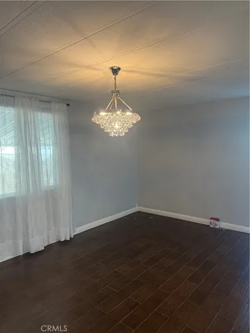 an empty room with wooden floor and chandelier
