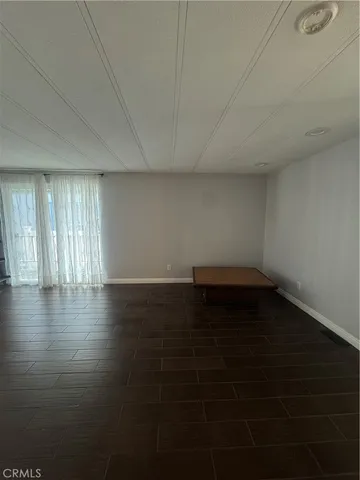 an empty room with wooden floor and windows with curtains
