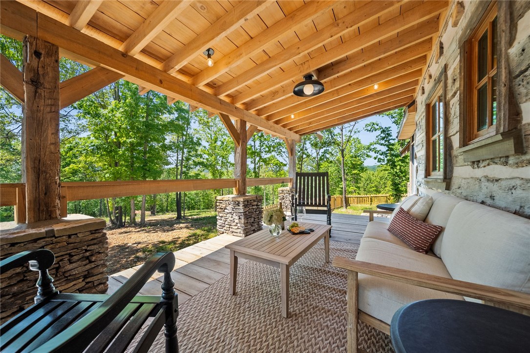 425 Barnhardt Road Timbo, AR 72680 - Photo 54 of 60 Covered porch featuring a wood-plank ceiling, exposed wood beams, and stone-clad pillar bases