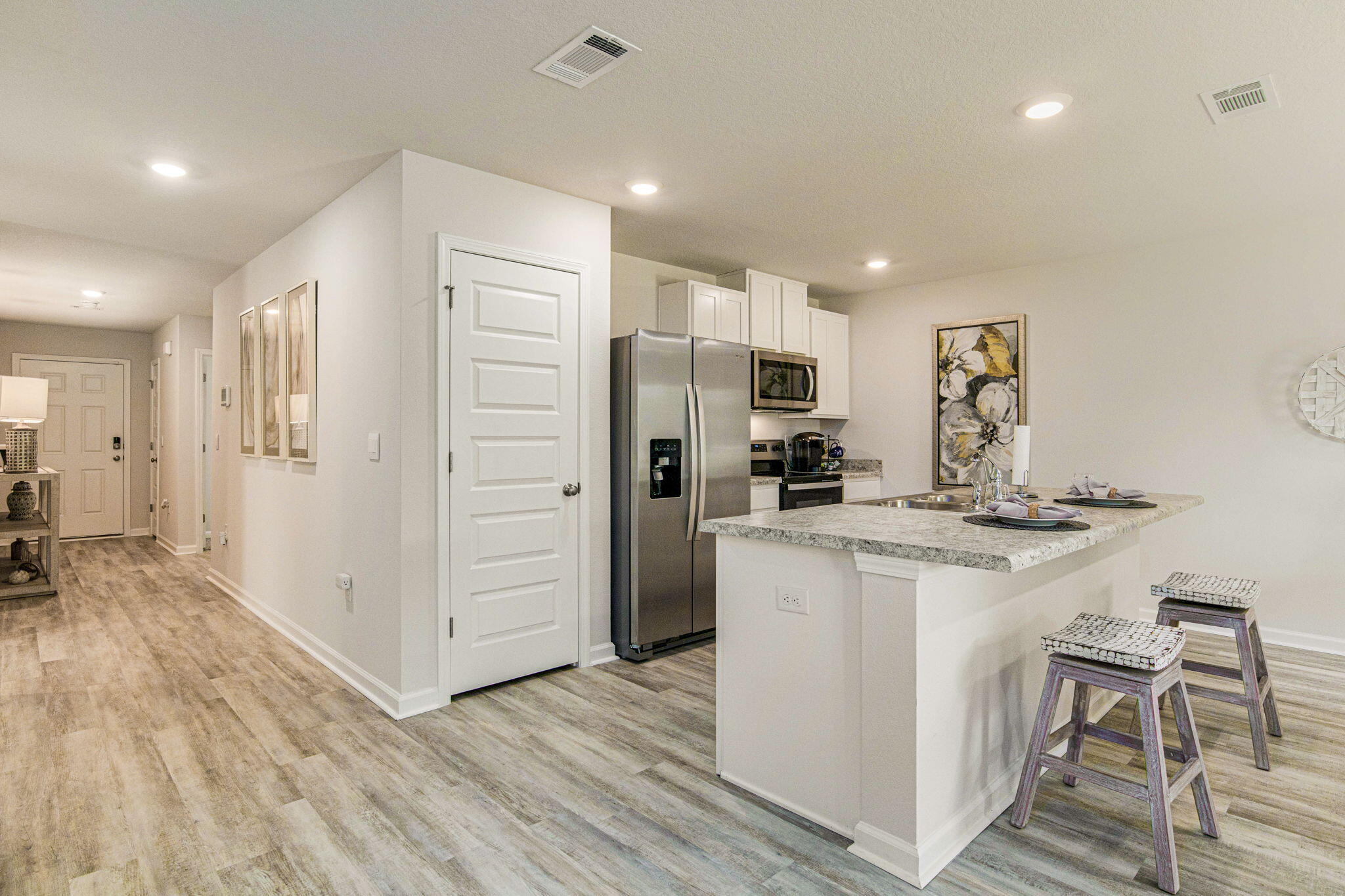 3064 Jane Lane Crestview, FL 32539 - Photo 7 of 33 a kitchen with kitchen island a refrigerator stove and white cabinets with wooden floor