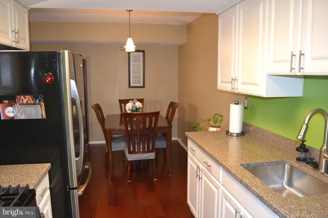 a kitchen with stainless steel appliances granite countertop a sink dishwasher a refrigerator with a dining table and chairs