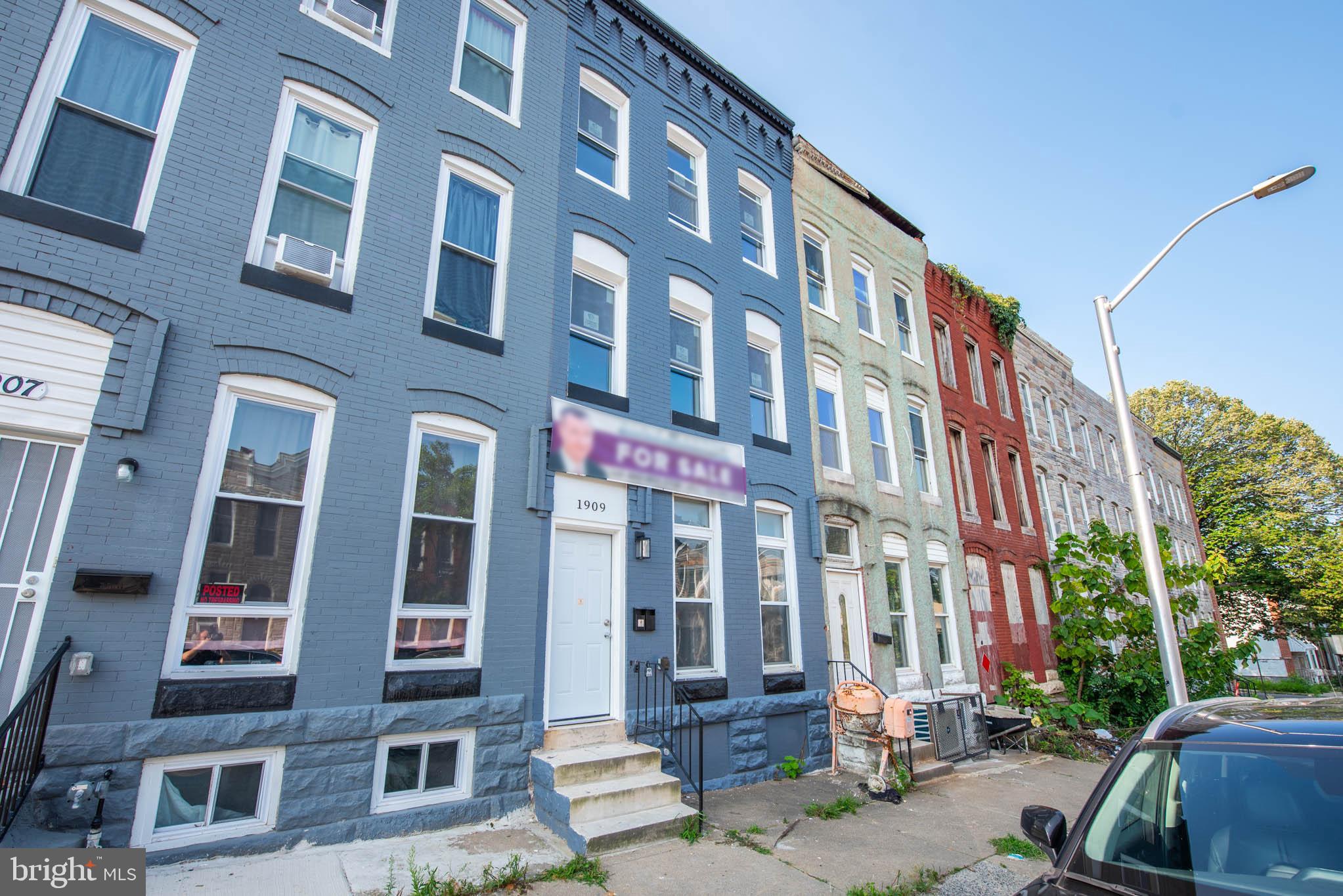 a front view of a building with lot of cars and trees