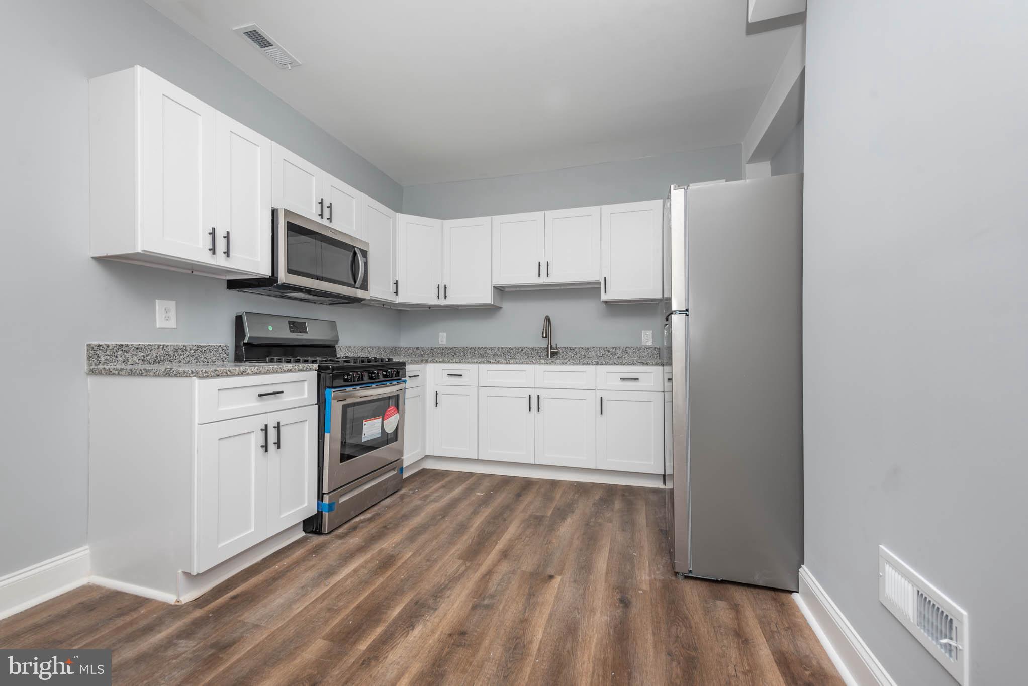 1909 Harlem Avenue Baltimore, MD 21217 - Photo 13 of 27 a kitchen with stainless steel appliances granite countertop white cabinets a sink a stove a microwave and white cabinets