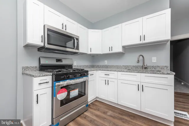 a kitchen with granite countertop white cabinets stainless steel appliances and a sink