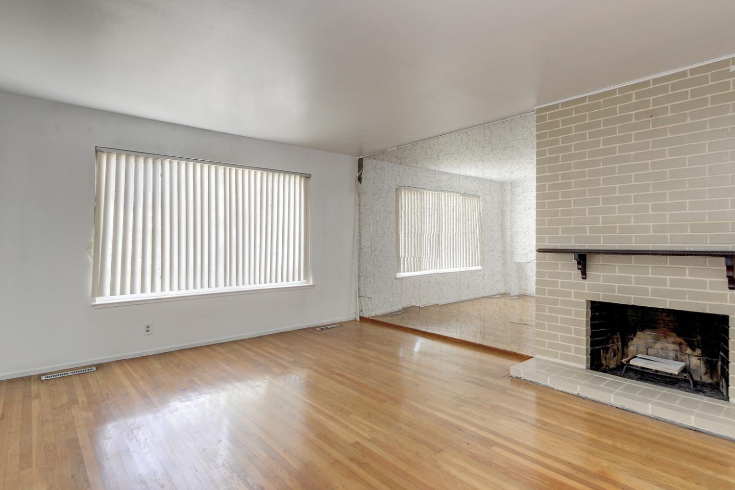 20631 McClellan Road Cupertino, CA 95014 - Photo 2 of 26 an empty room with wooden floor fireplace and windows