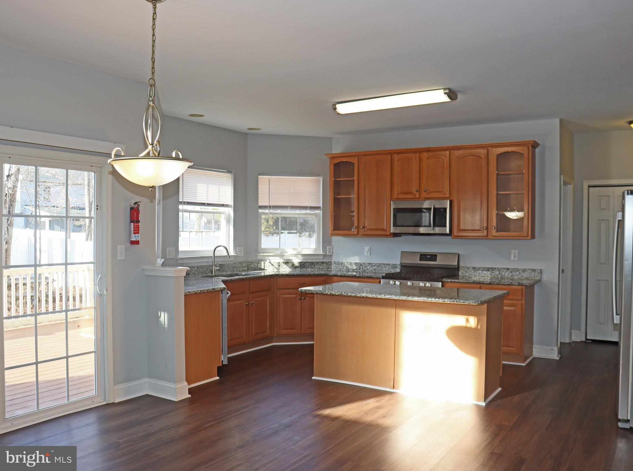 24 Blue Spruce Drive Bear, DE 19701 - Photo 3 of 13 a kitchen with stainless steel appliances granite countertop wooden floors and white cabinets