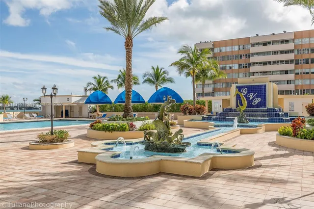 a view of swimming pool with lawn chairs potted plants and palm trees
