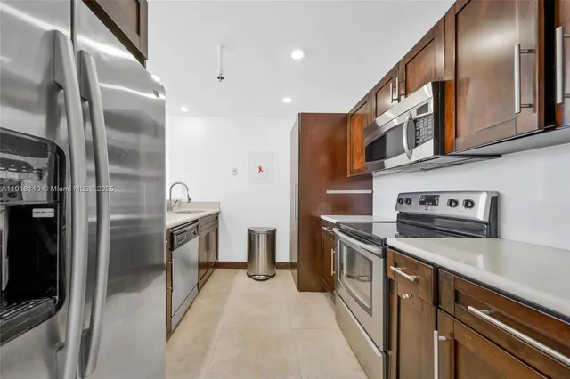 a kitchen with stainless steel appliances granite countertop a refrigerator a stove and a sink