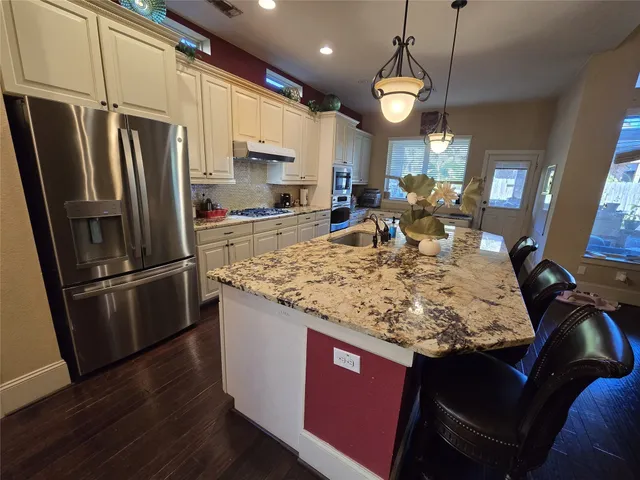 a kitchen with sink refrigerator dining table and chairs