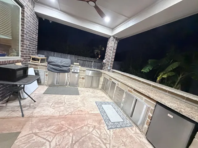 a outdoor kitchen with a sink and chairs