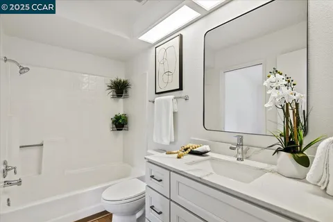 a bathroom with a granite countertop sink a toilet and a large mirror