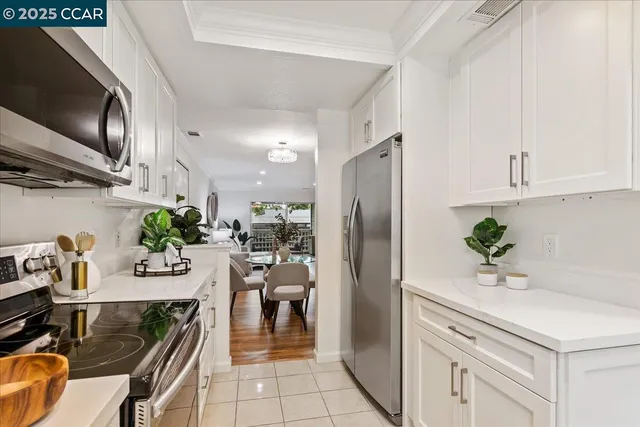 a kitchen with stainless steel appliances kitchen island granite countertop a refrigerator a sink a stove and white cabinets