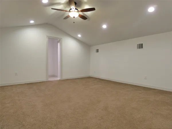 an empty room with a chandelier fan and windows