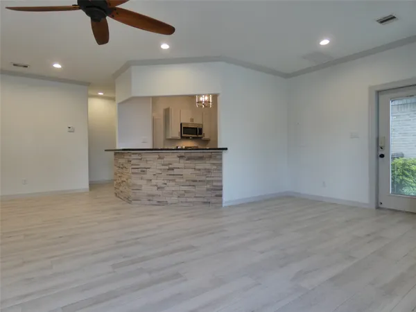 a view of an empty room with wooden floor and a ceiling fan
