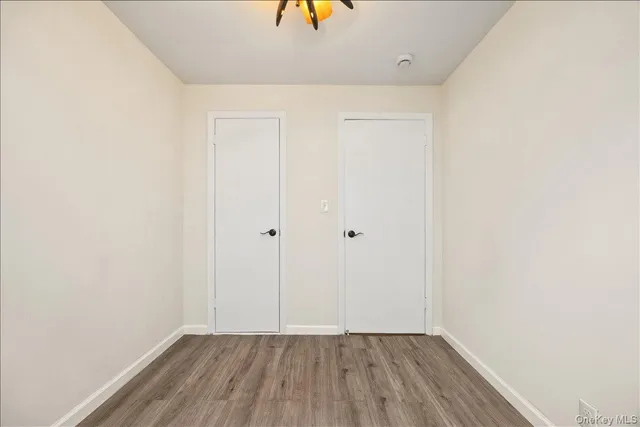 a view of an empty room with closet and wooden floor