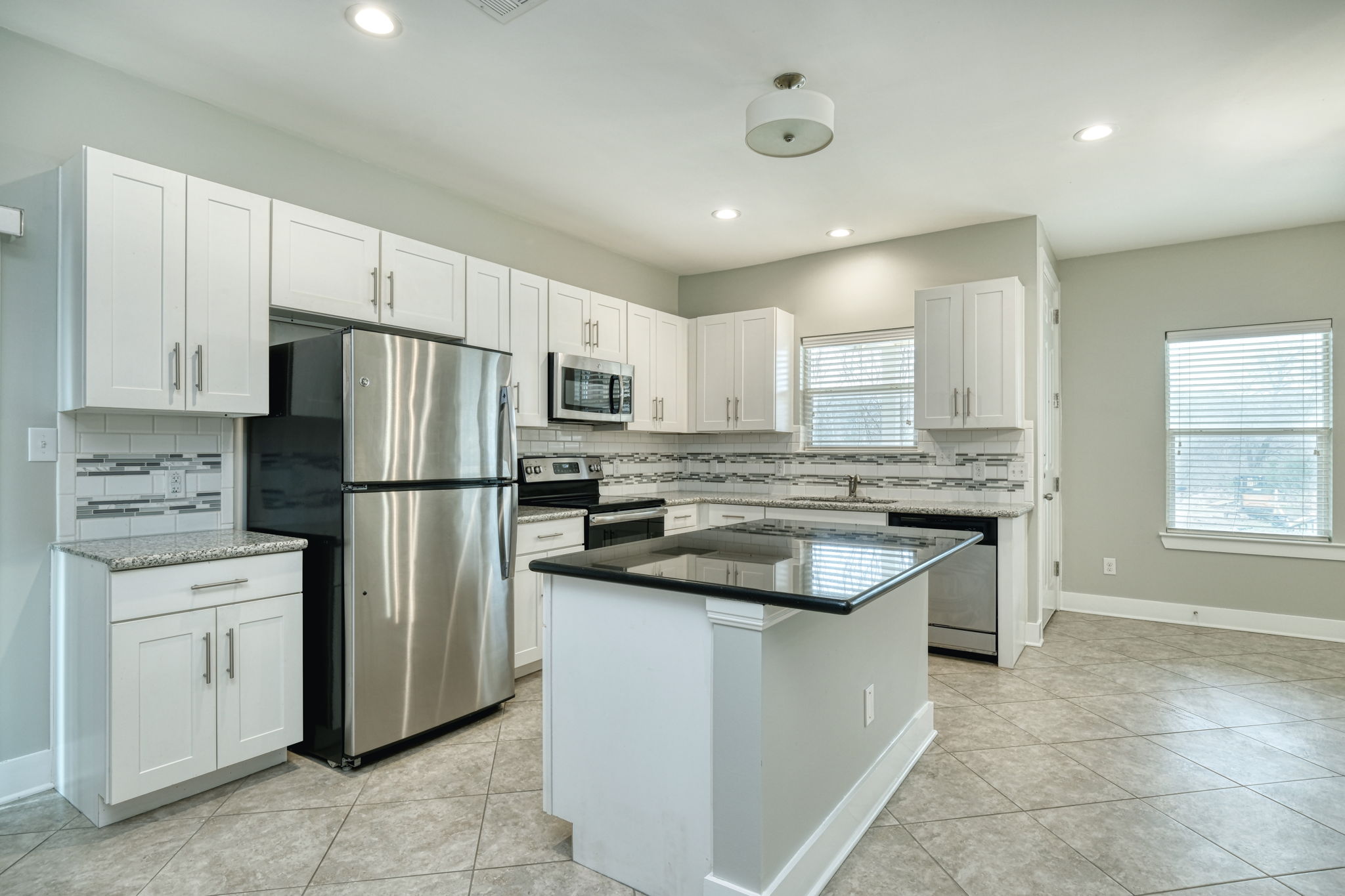 605 Pecan Avenue, Unit 3 Round Rock, TX 78664 - Photo 2 of 15 Kitchen with appliances with stainless steel finishes, white cabinets, decorative backsplash, a center island, and recessed lighting
