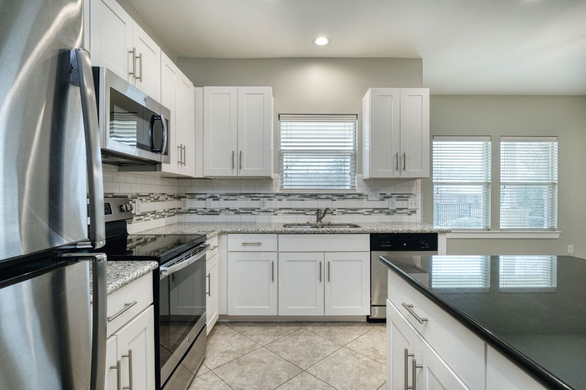 605 Pecan Avenue, Unit 3 Round Rock, TX 78664 - Photo 3 of 15 Kitchen with appliances with stainless steel finishes, white cabinets, dark stone countertops, and recessed lighting