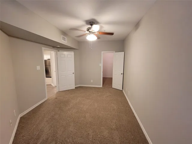 a view of an empty room with a chandelier fan