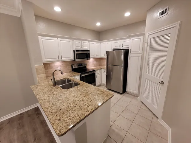 a kitchen with stainless steel appliances granite countertop a refrigerator and a sink