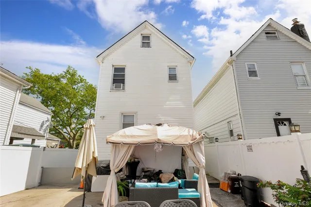 a view of a white house with a small yard and furniture