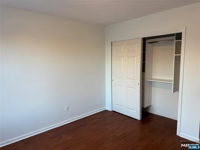 a view of an empty room with wooden floor & closet