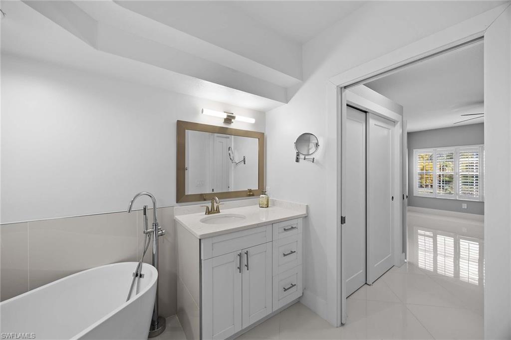 6834 Lantana Bridge Road, Unit 101 Naples, FL 34109 - Photo 32 of 50 a bathroom with a tub sink and mirror
