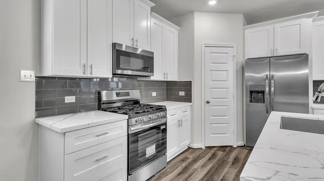 a kitchen with stainless steel appliances white cabinets and a stove top oven
