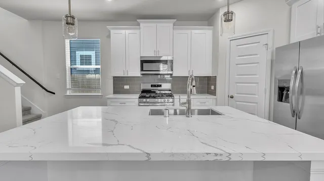 a large white kitchen with stainless steel appliances