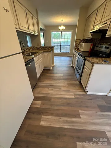 a kitchen with granite countertop wooden floors and stainless steel appliances