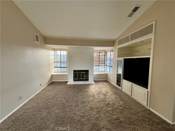 an empty room with windows and fireplace