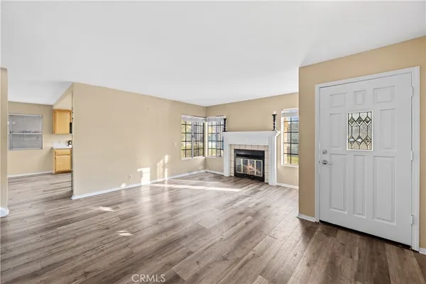 an empty room with wooden floor fireplace and windows