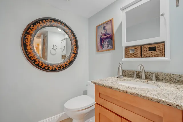 a bathroom with a granite countertop toilet a sink and a mirror